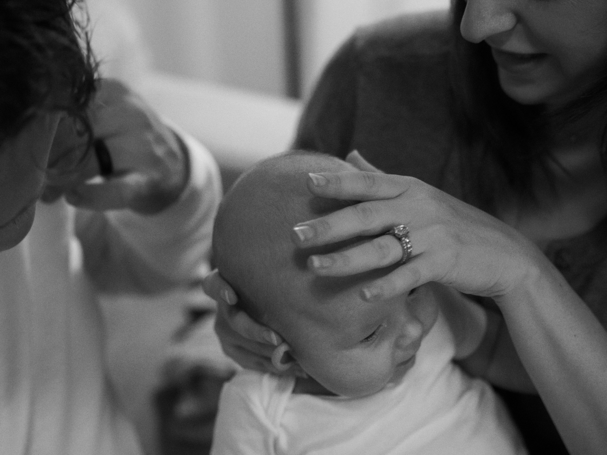 Black and white close-up of parents gently holding their baby