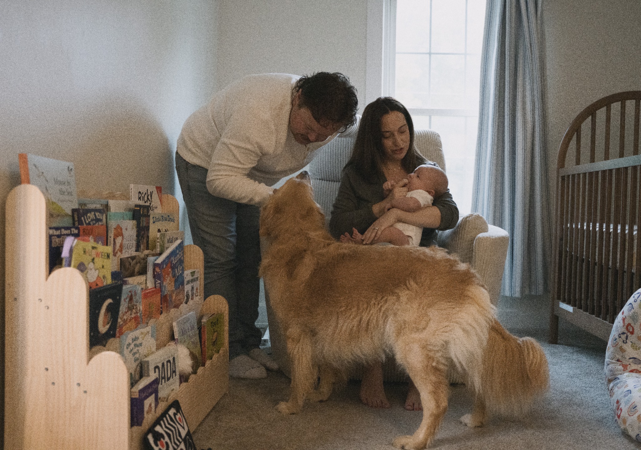 Parents, baby, and their dog together in the nursery